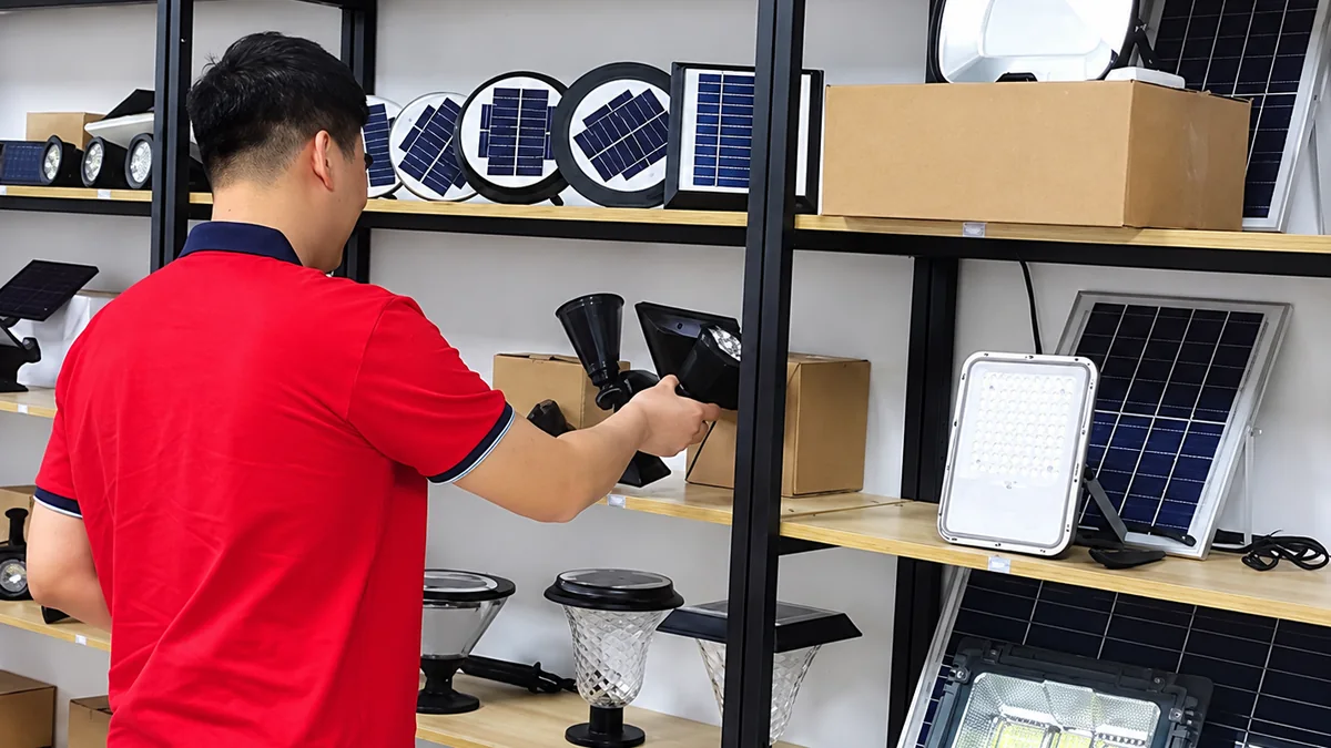 Buyer inspecting a solar wall light sample on a shelf of solar panels and boxed light models